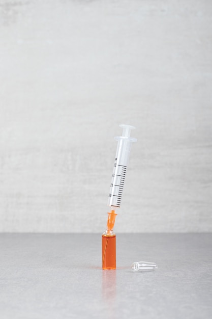 Small syringe with brown liquid on gray surface