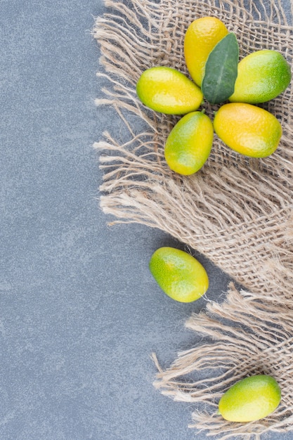 Free photo small tangerines with burlap on marble.