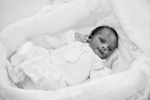 Small tiny newborn african american baby laying on the bed Black and white photo