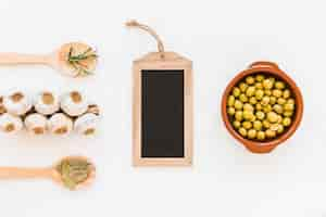 Free photo small wooden chalk board with bunch of garlic bulbs, olives and herbs