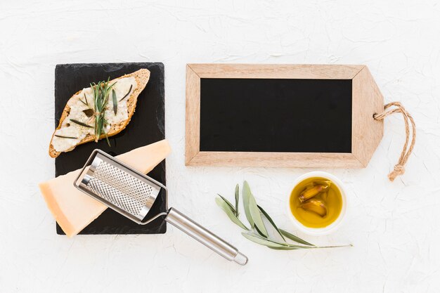 Small wooden slate with bread, cheese and oil on white background