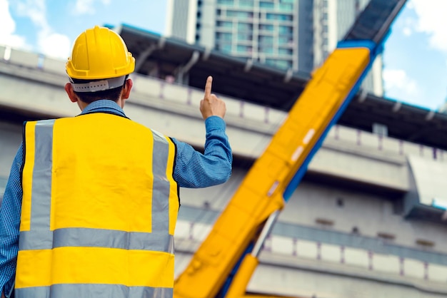 Smart asian engineer manager with safety uniform checking site construction with steel and concrete sturcture background