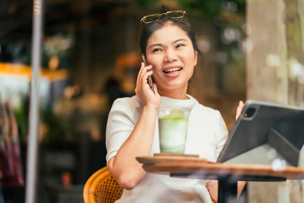 Smart attractive positive asian digital nomad female wearing casual cloth work remote new normal lifestyle hand use tablet tele conference onlive videocall meeting remote at coffeeshop cafe