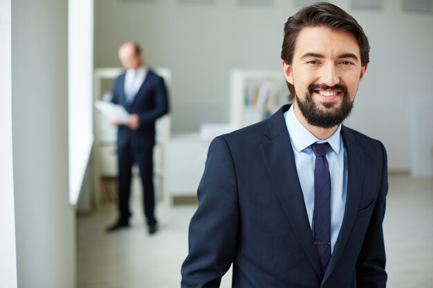 Smart businessman with teammate in the background