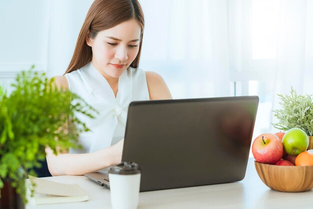 Smart executive asian woman white dress meeting with coworker with laptop presentation office background