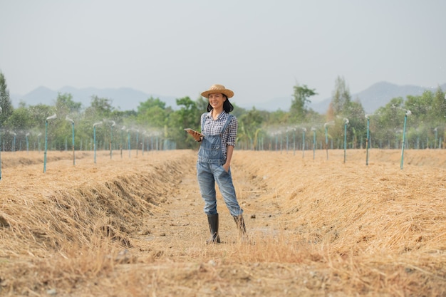 Free photo smart farm. beautiful farmer use tablet to control her farm and business with happy and smile. business and agriculture concept. farmer or agronomist examine prepare a plot for growing vegetables.