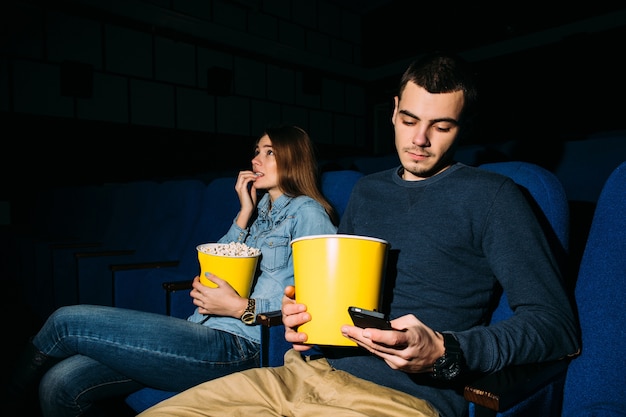 Free photo smart phone in cinema. man using smartphone while watching movie at the cinema.