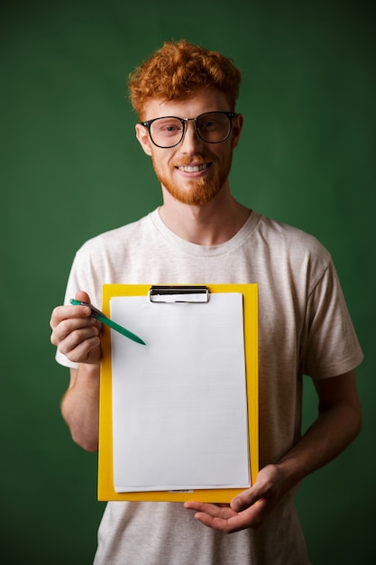 Free photo smart readhead bearded man in white tshirt showing folder with copyspace