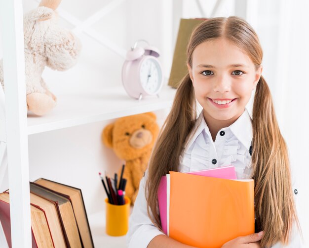 Smart schoolgirl standing with copybooks