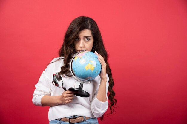 Smart woman posing with globe and magnifying glass. High quality photo