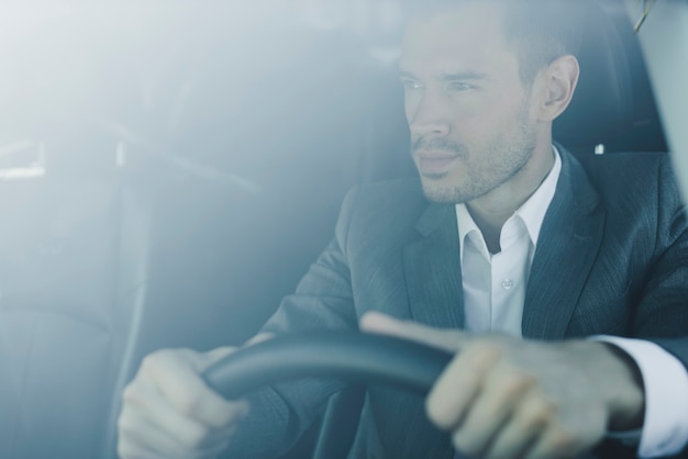 Free photo smart young businessman driving the car