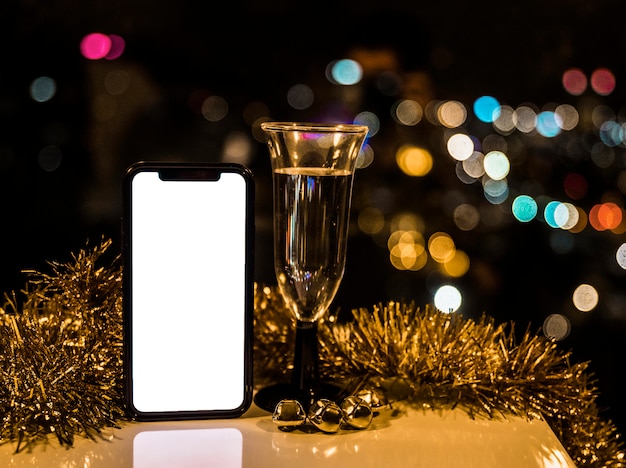 Smartphone near glass of drink and tinsel 