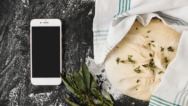 Free photo smartphone; raw dough; thymes on kitchen worktop