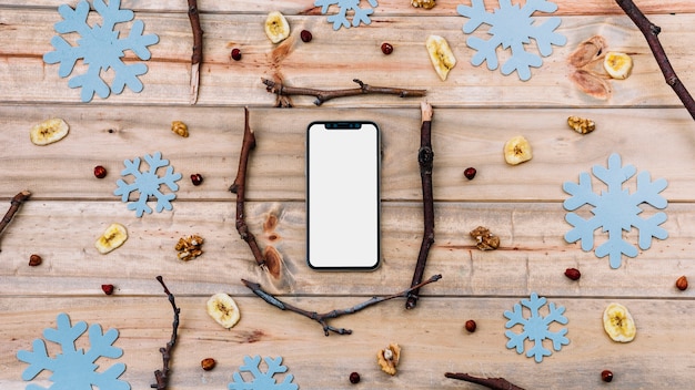 Free Photo smartphone between twigs and decorative snowflakes