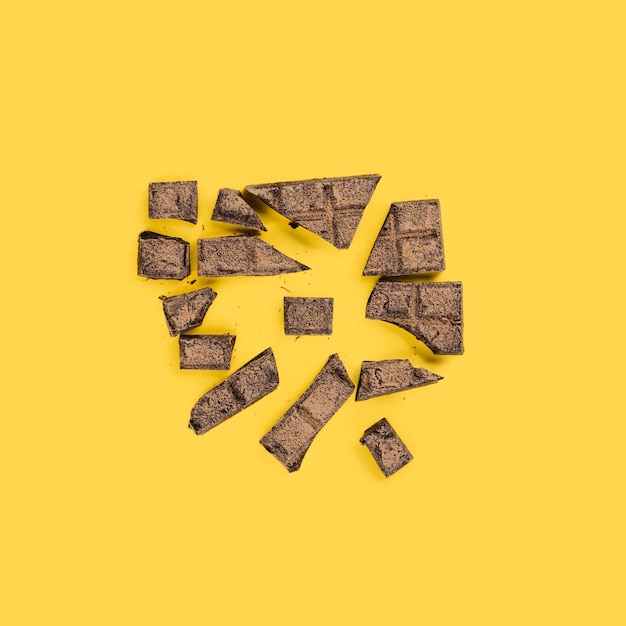 Free photo smashed pieces of chocolate on yellow surface