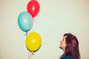 Free photo smiely young woman looking at balloons