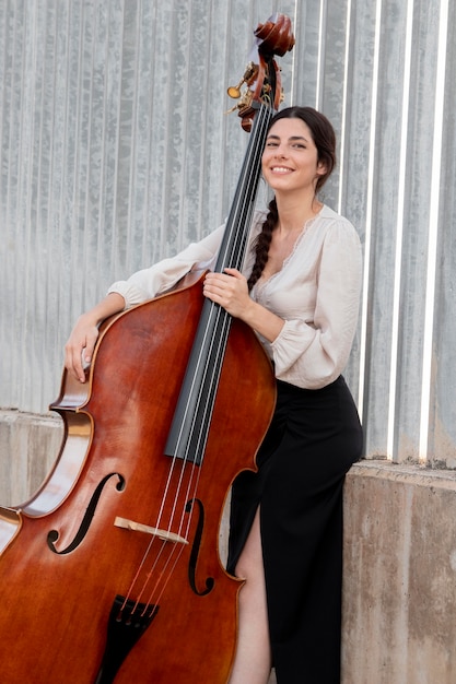 Free Photo smiley artist with double bass medium shot