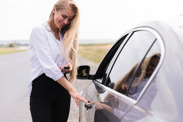 Smiley beautiful woman opening the car door