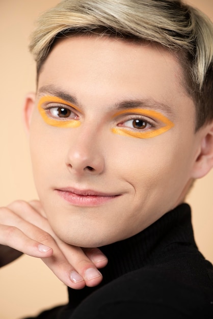 Smiley blonde man wearing orange eyeliner