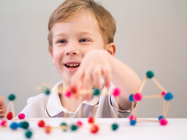 Smiley boy playing with colorful atoms game