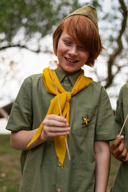 Free photo smiley boy scout with marshmallow front view