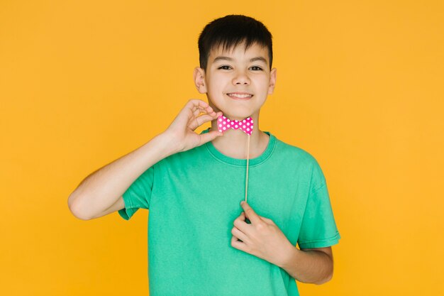 Free Photo smiley boy trying on a fake bow tie