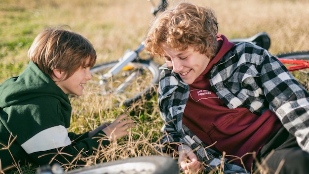 Smiley boys relaxing on grass while riding their bicycles