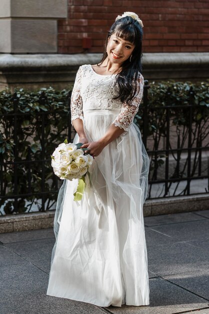 Smiley bride posing on the street with bouquet