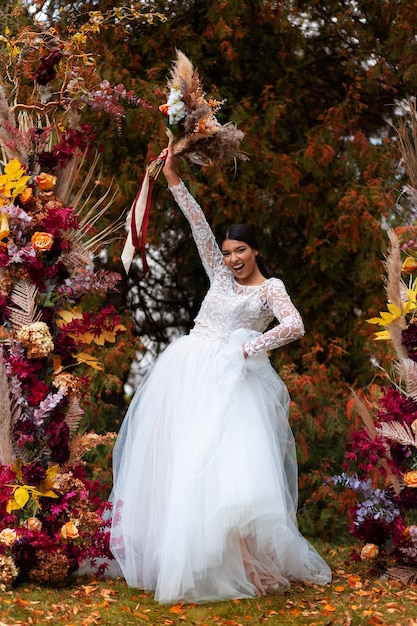 Free photo smiley bride posing with flowers full shot