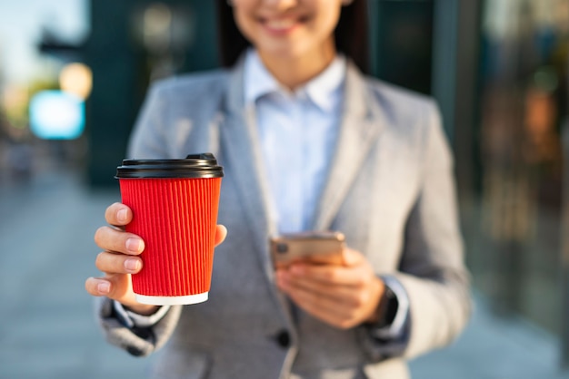 Smiley businesswoman using smartphone while having coffee