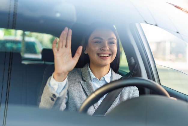 Free photo smiley businesswoman waving from her car