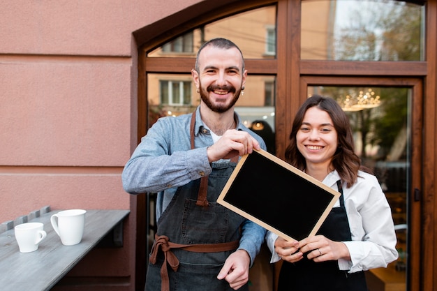 Smiley coffee shop owners holding frame