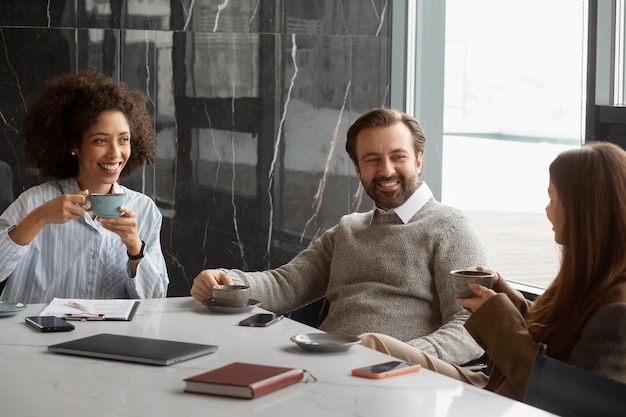 Free photo smiley colleagues with coffee cups at job