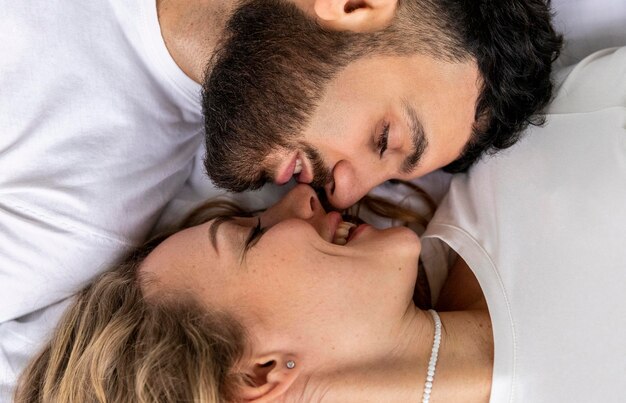 Smiley couple kissing in bed at home