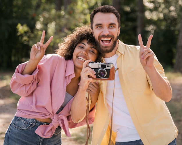 Smiley couple outdoors taking pictures with camera