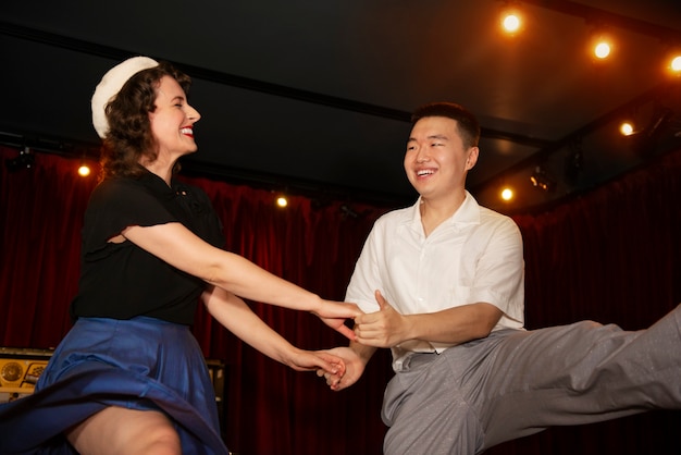 Free photo smiley couple swing dancing low angle