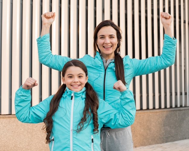 Smiley daughter and mom showing muscles