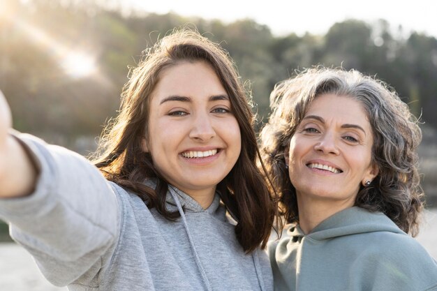 Smiley daughter taking a selfie with her mother outdoors