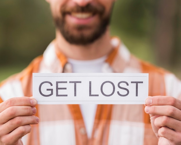 Free photo smiley defocused man holding get lost sign