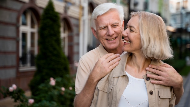 Smiley elder couple posing together while taking a walk in the city