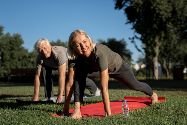 Smiley elder couple practicing yoga outdoors