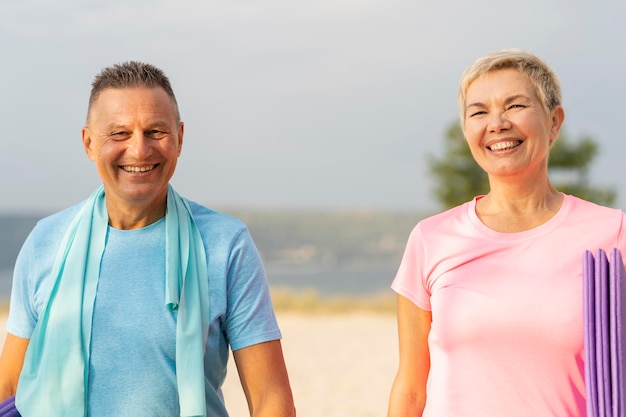 Smiley elder couple with working out equipment on the beach