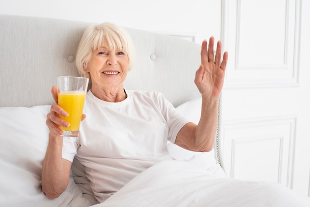 Smiley elder woman holding a glass with juice