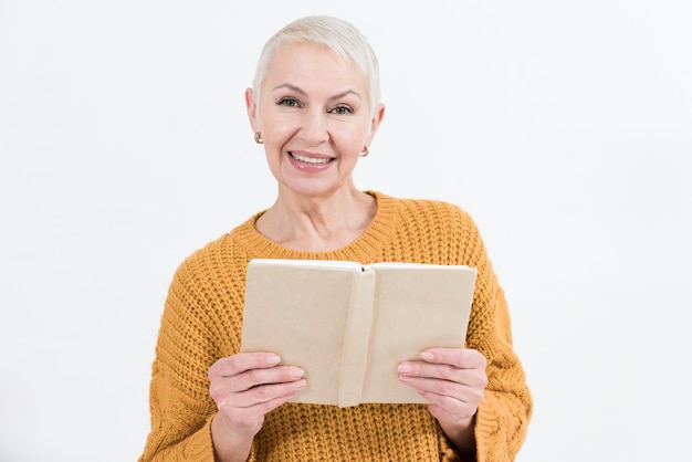 Smiley elder woman posing while holding book