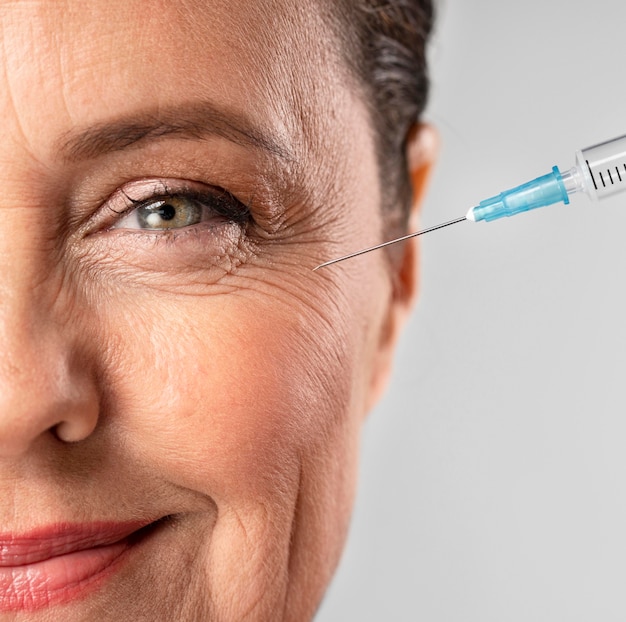 Free photo smiley elder woman using injection for her eye wrinkles