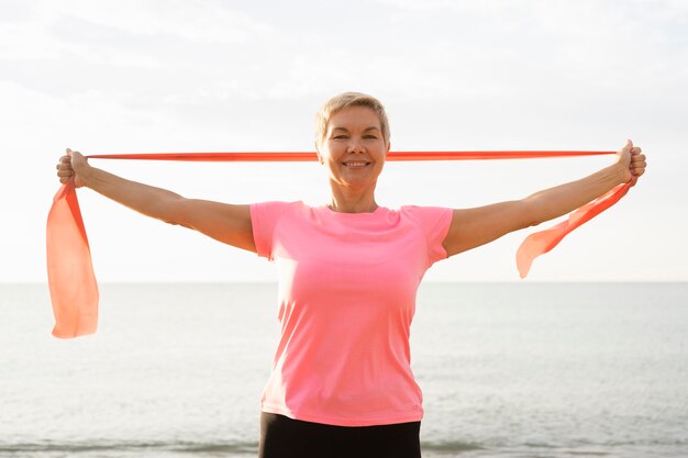 Smiley elder woman with elastic rope on the beach