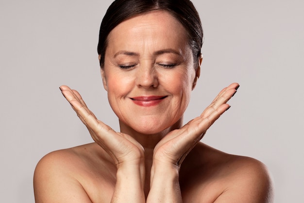 Smiley elder woman with make-up on preparing for skin care