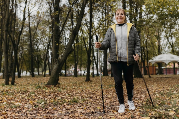 Smiley elder woman with trekking sticks and copy space