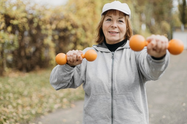 Free Photo smiley elderly woman working out with weights