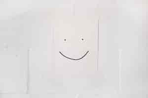 Free photo smiley face made on white paper stick on wall with tape